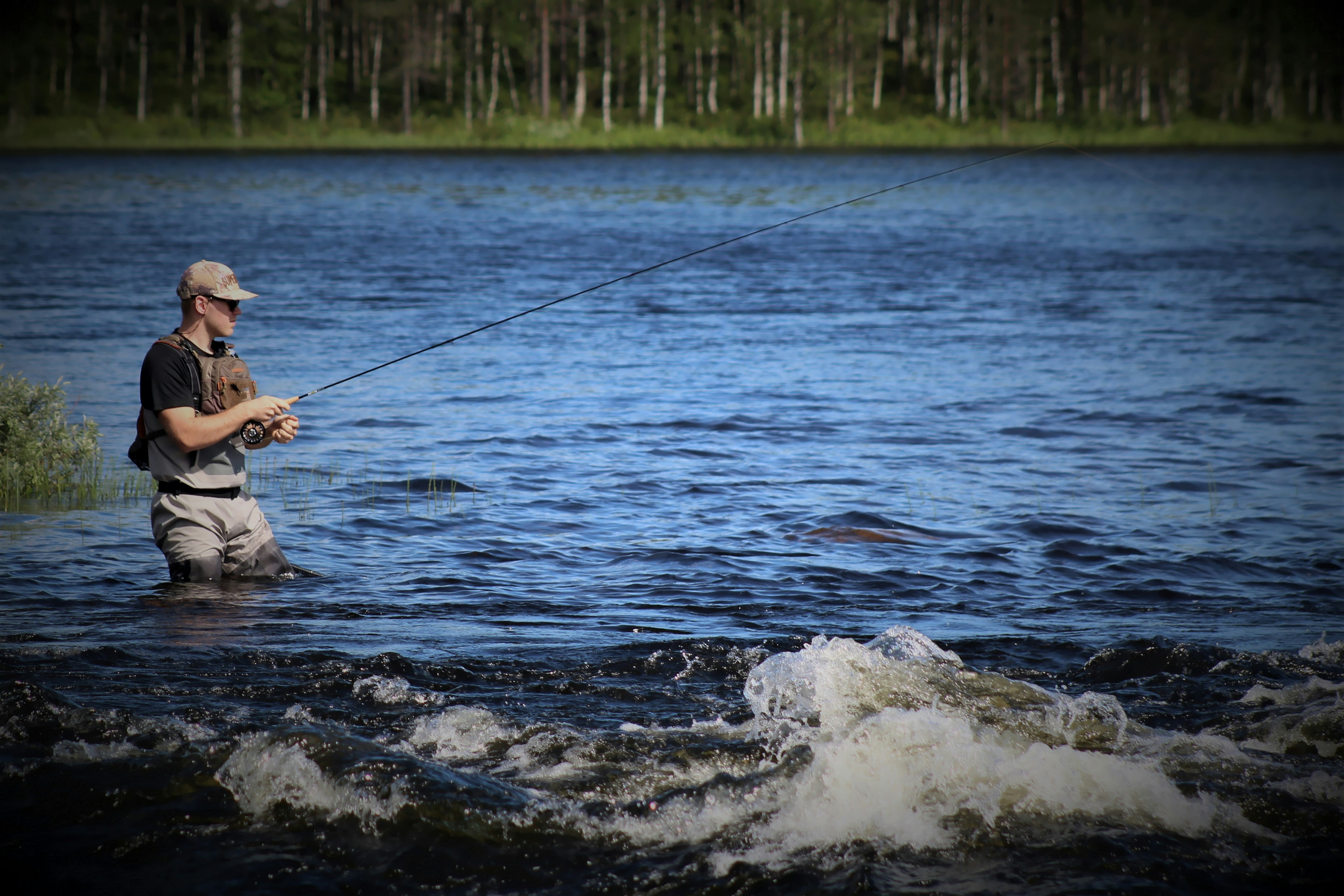 Fly fisherman casting from the bank of a stillwater lake